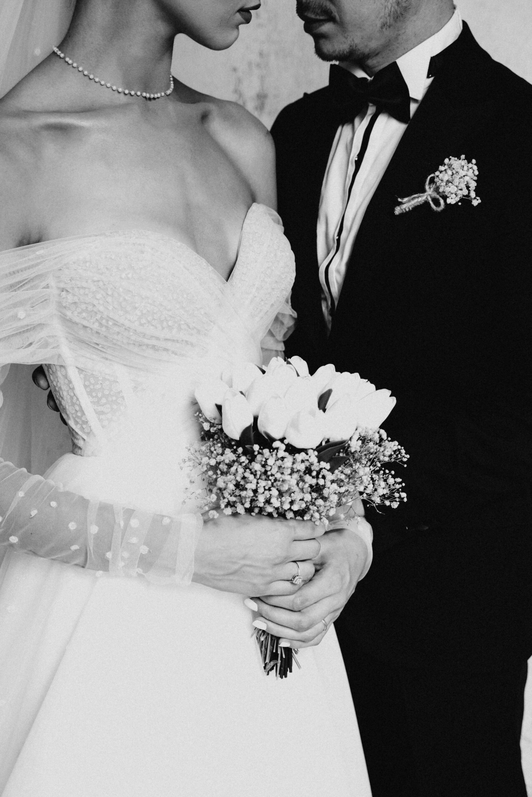 Black and white portrait of a bride and groom holding a bouquet.